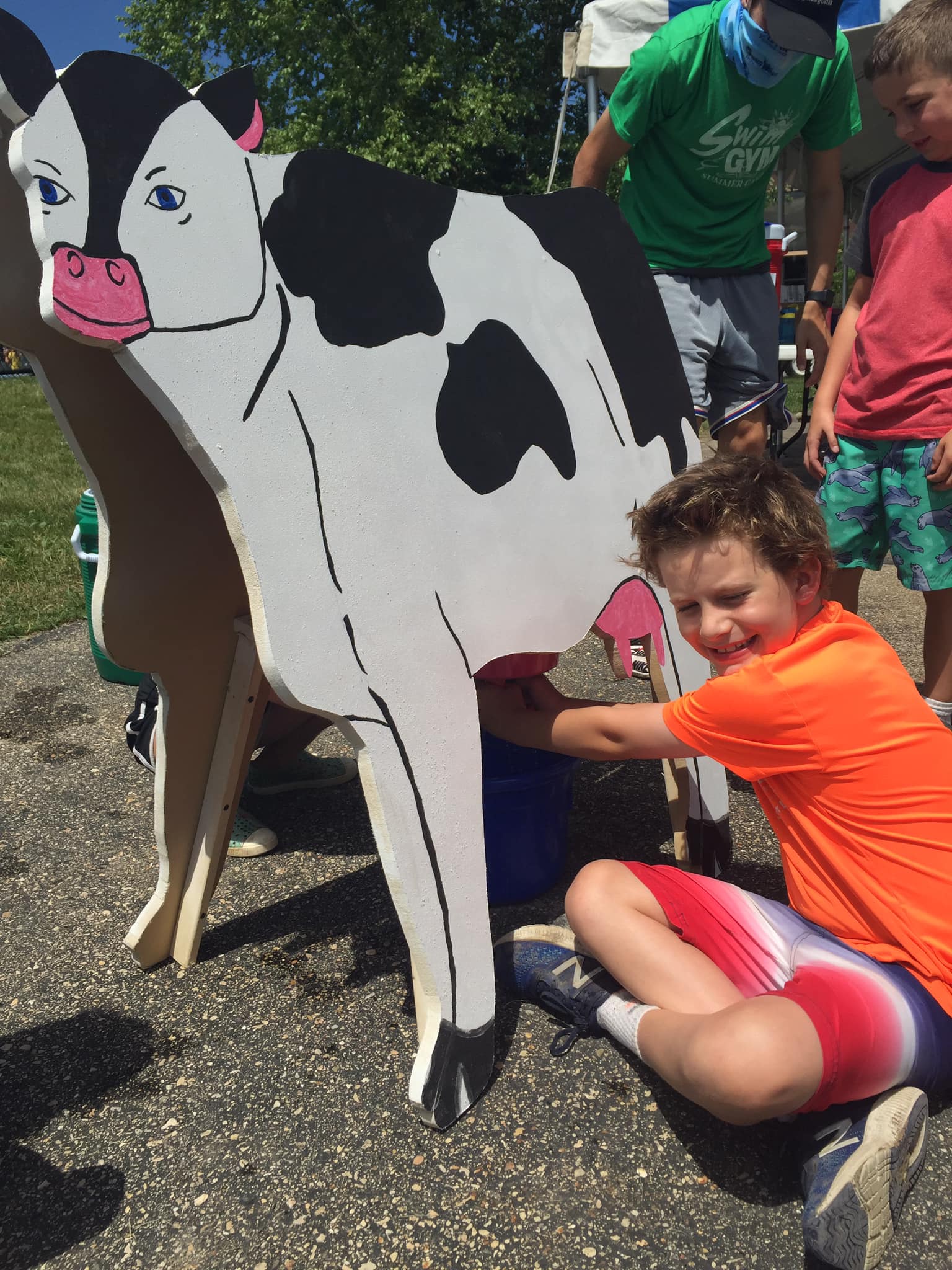 Camper posing beside a painted cow cutout during a camp outing