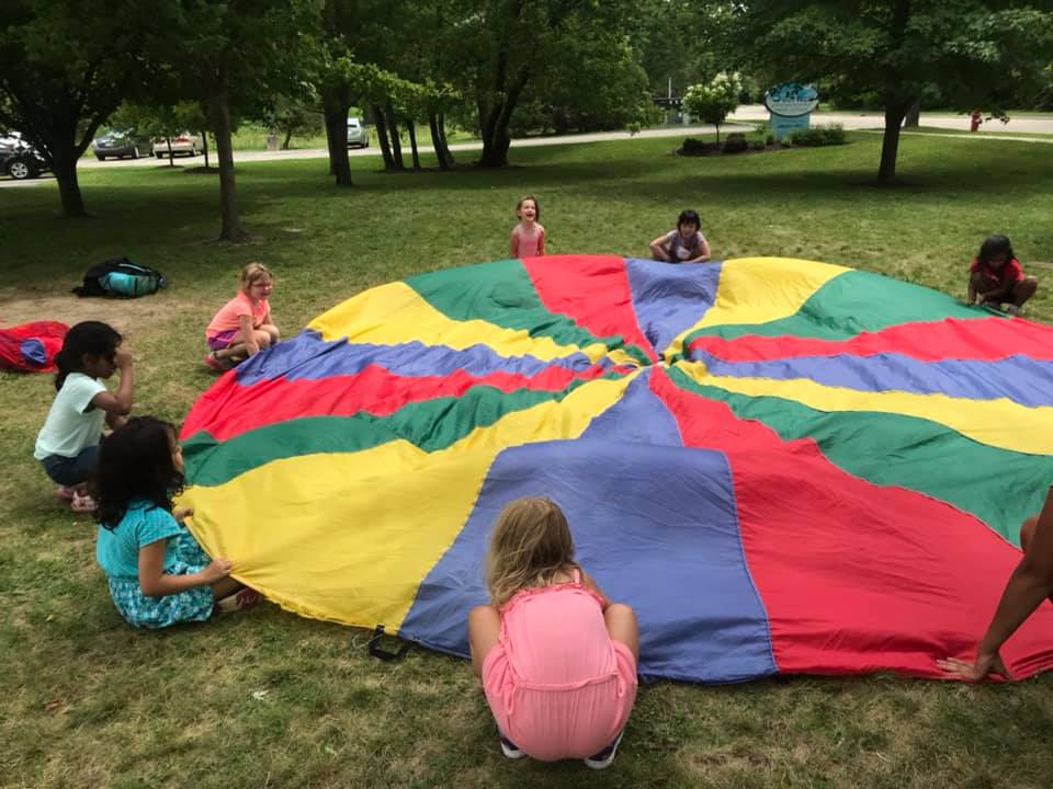 Campers playing a parachute game on the grass