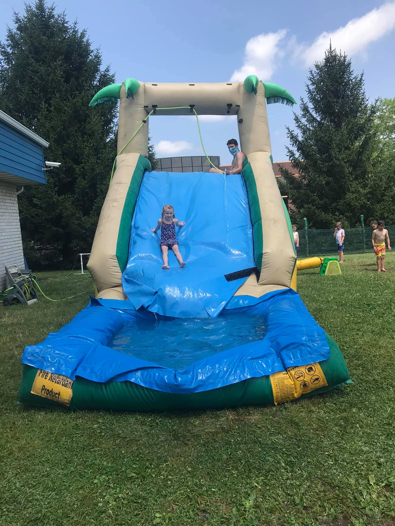 Camper sliding down the big inflatable water slide at summer camp