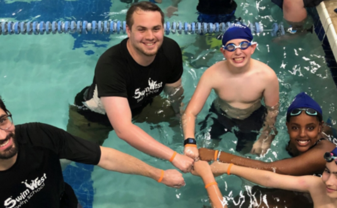 Counselor giving a camper a fist bump during swim time