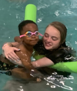 Counselor supporting a camper during a swim lesson