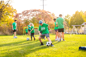 Campers playing soccer on the field at camp